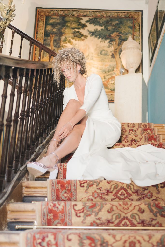 Reportaje de bodas novia atándose los zapatos en la escalera antes de ir a la ceremonia
