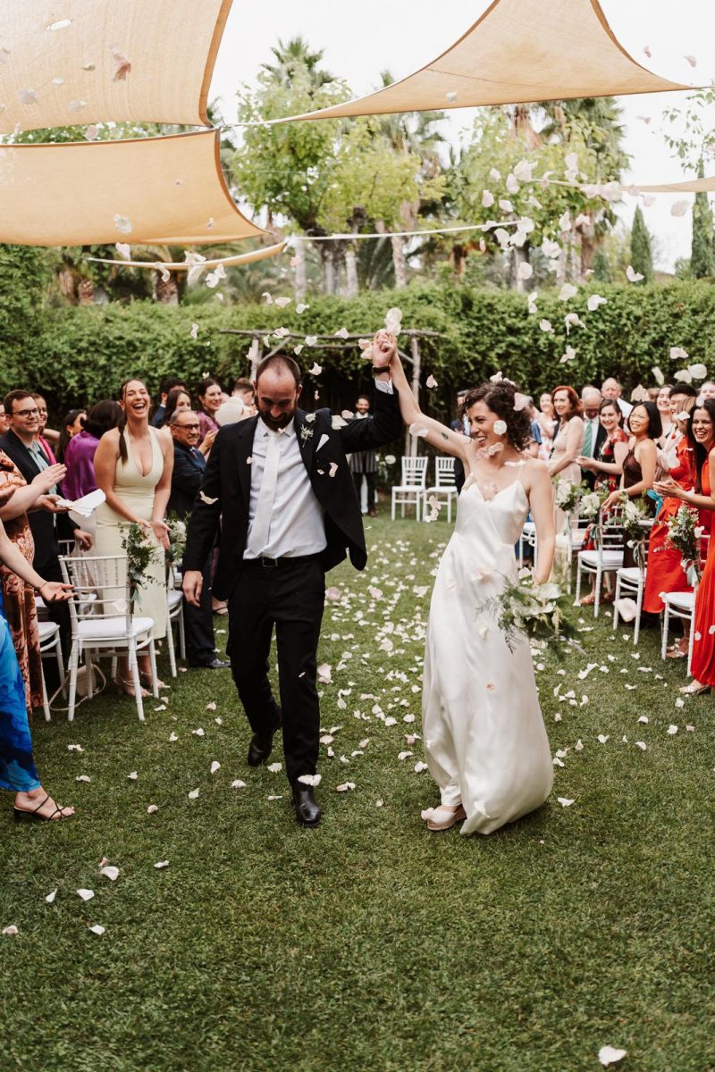 novios en la salida de su ceremonia cuando los invitados les tiran pétalos