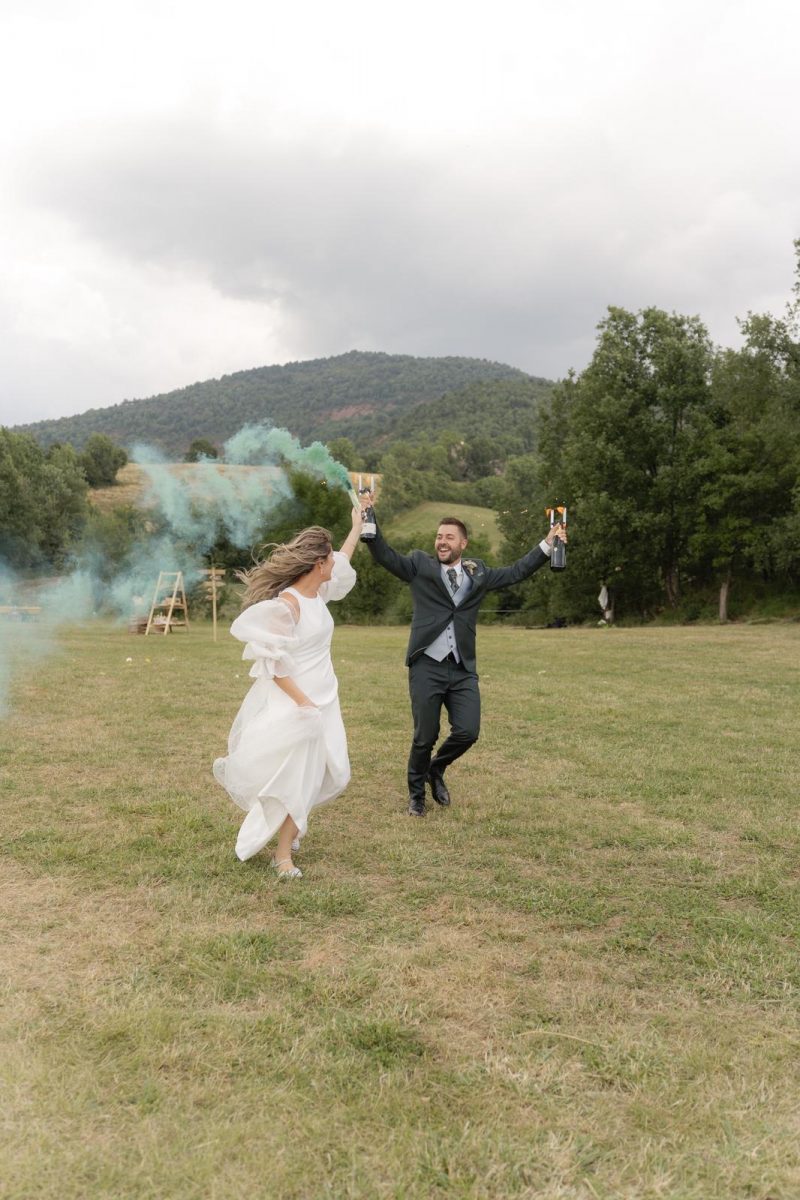 Novios llegando al cóctel con bengalas de humo de colores