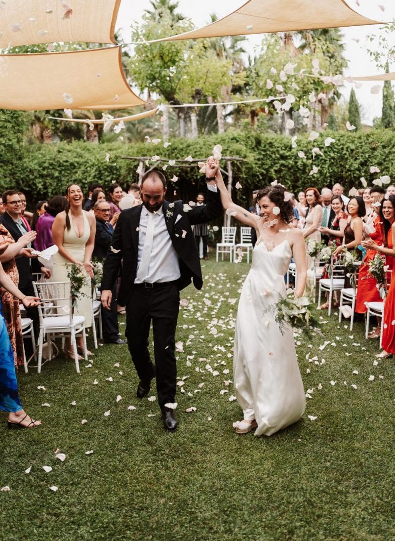 novios en la salida de su ceremonia cuando los invitados les tiran pétalos