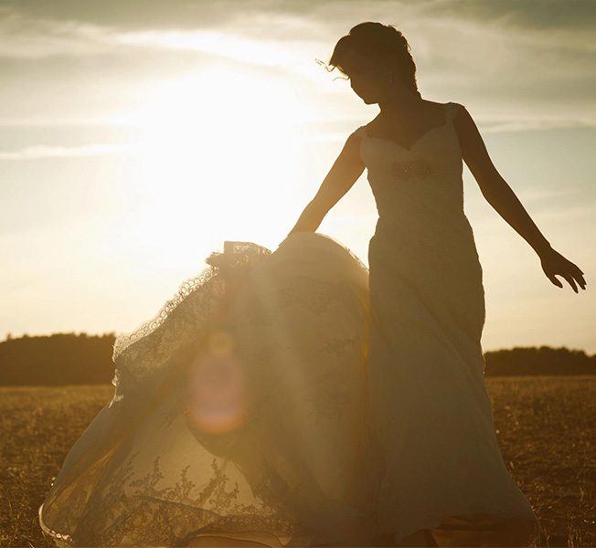 Boda en España y novia que pasea al atardecer por el campo con su vestido de novia