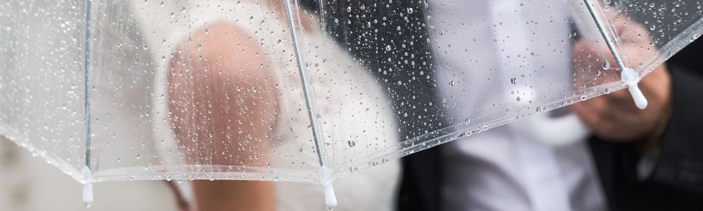 Novios el día de su boda debajo de un paraguas transparente